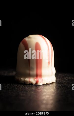 Sweet foam dessert. Marshmallow covered with strawberry icing on black table. Stock Photo