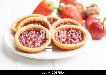 Sweet biscuits with strawberries jam and strawberries on white table. Stock Photo