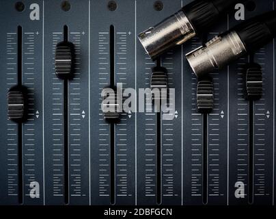 Audio mixer with foreground faders and audio cables with xlr connectors Stock Photo
