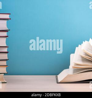 A large, thick hardcover book is lying on a light-wood table. The book is open, the pages are fanned out, and on the back is a blue background with sp Stock Photo