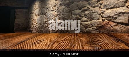 Old stone wall with empty rustic wooden table in a basement. Horizontal background for a decoration. Space for concept, design and text. Stock Photo