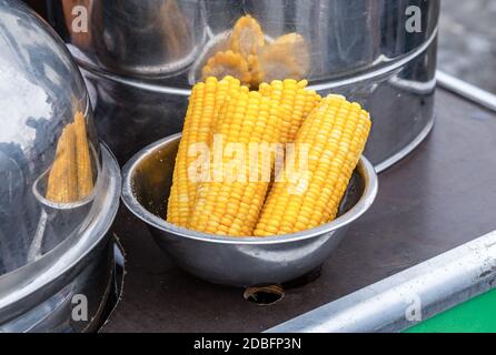 Steamed corn in a cooking saucepan, street food. Boiled corn cobs with a bit of sugar or salt to get a delicious taste Stock Photo
