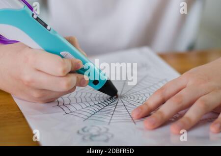 Child using 3D pen. Boy draws on stencil by colored ABS plastic at home. Creative hobby at home, technology, leisure, education concept. Selective foc Stock Photo