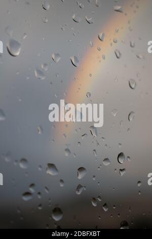 Rainbow seen thru wet window with water drops Stock Photo
