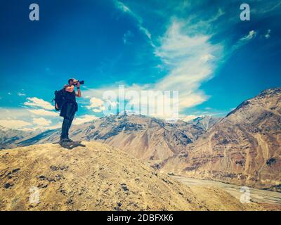 Vintage retro effect filtered hipster style image of photographer taking photos in Himalayas mountains. Spiti valley, Himachal Pradesh, India Stock Photo