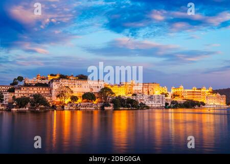 Rajasthan indian tourist landmark - Udaipur City Palace complex in the evening twilight with dramatic sky - panoramic view. Udaipur, India Stock Photo