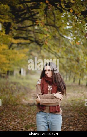 Beautiful long haired woman in warm scarf in autumn park. Stock Photo