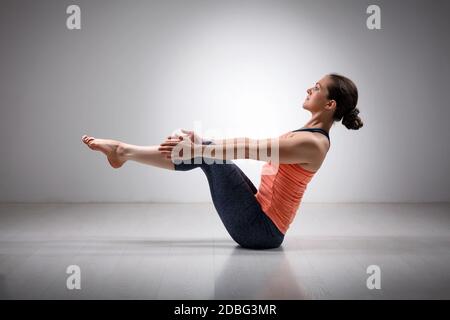 Beautiful sporty fit yogini woman practices yoga asana Paripurna navasana - boat  pose isolated on white background - SuperStock
