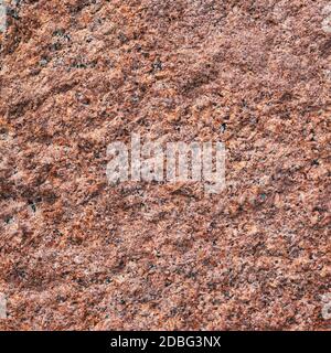 Background granite is a red stone with small black and white spots on the entire surface. Texture for an inscription, text, or logo. Stock Photo