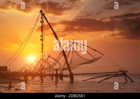 Kochi chinese fishnets on sunset. Fort Kochin, Kochi, Kerala, India. With lens flare and light leak Stock Photo
