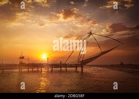 Kochi chinese fishnets on sunset. Fort Kochin, Kochi, Kerala, India. With light leak and lens flare Stock Photo
