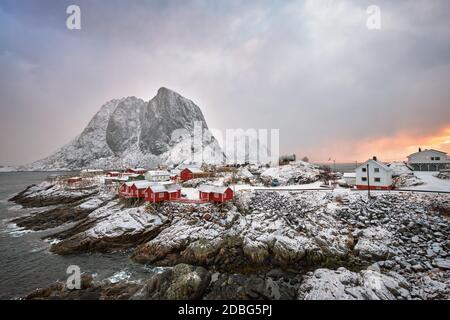 Famous tourist attraction Hamnoy fishing village on Lofoten Islands, Norway with red rorbu houses. With falling snow in winter on sunrise Stock Photo