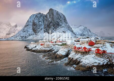 Famous tourist attraction Hamnoy fishing village on Lofoten Islands, Norway with red rorbu houses. With falling snow in winter on sunrise Stock Photo