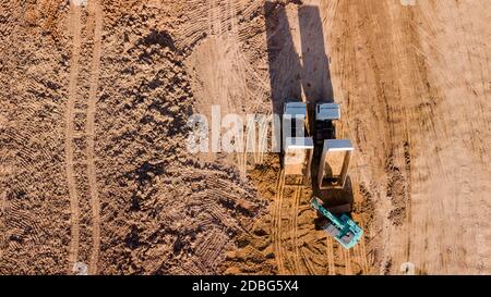 Construction site aerial view There are backhoes and dump trucks shoot from drone fly Stock Photo