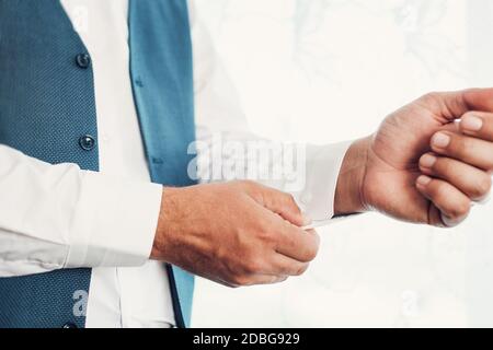 The man fastens the buttons on the shirt. Morning of the groom. Hands of wedding groom buttoning up his white shirt. Stock Photo