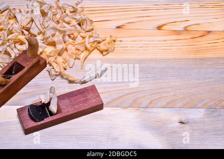 Japanese wooden plane close-up with a pile of shavings on a smooth wooden surface. Background. The view from the top. Stock Photo