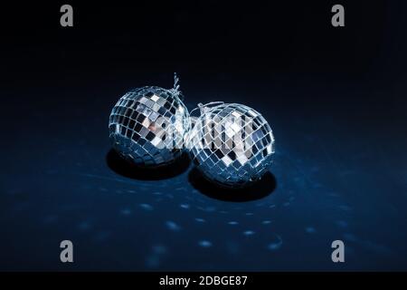 two mirror balls illuminated by bright light lie on dark blue background with reflections Stock Photo