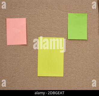 blank pink, yellow and green papers glued on a brown cardboard surface. Design template. Stock Photo