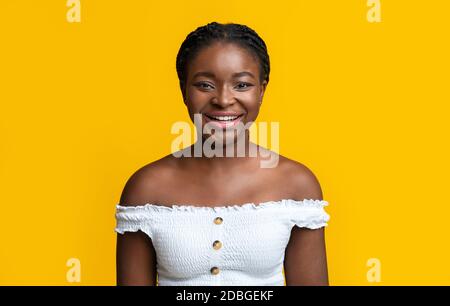 Portrait of young smiling african american woman with braids over yellow background Stock Photo