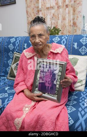 Portrait of a 0ne hundred and one year old woman holding a sixty year old photo of herself in New York City. Stock Photo