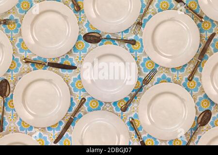 Pattern of vintage dinner plates, knives, forks and spoons on a flower cloth Stock Photo
