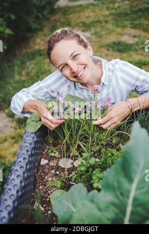 beautiful woman posing next to raised garden bed and her fresh vegetables Stock Photo