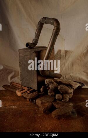 Recycled, old pipe on wooden block with rusty wrenches in front with gloves Stock Photo