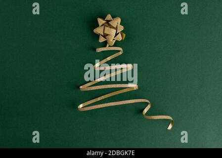 Christmas tree made from gold sparkling ribbon on a bright green backdrop. Merry Christmas and Happy New Year festive background with empty space for Stock Photo