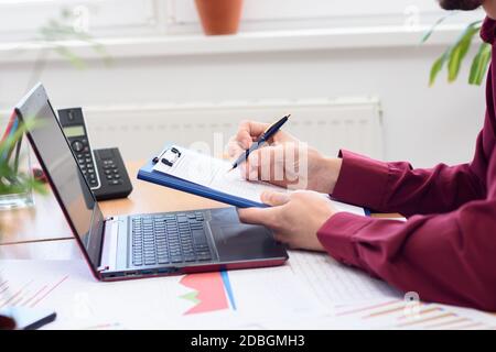close-up of hands of men making notes in a notebook against the background of the desktop Stock Photo
