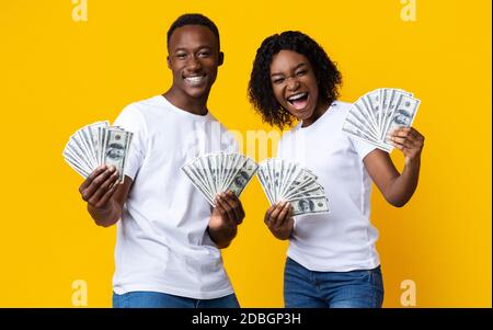 Joyful black couple won lottery, showing prize at camera, screaming Stock Photo
