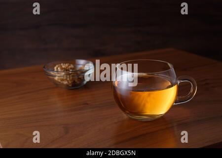 Black tea in a glass cup and walnuts in a bowl Stock Photo