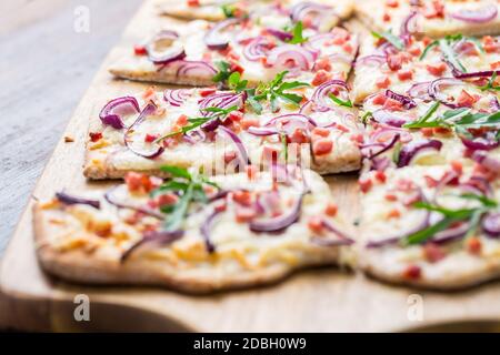 Traditional French dish tarte flambee cream cheese, bacon and onions. Flammkuchen from Alsace region. Flame cake. Stock Photo