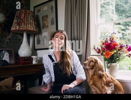 Interior designer Flora Soames and her dog Humbug, photographed at her Wiltshire home. Flora wears Carrier Company dungarees, With Nothing Underneath Stock Photo