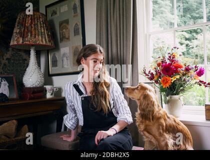 Interior designer Flora Soames and her dog Humbug, photographed at her Wiltshire home. Flora wears Carrier Company dungarees, With Nothing Underneath Stock Photo