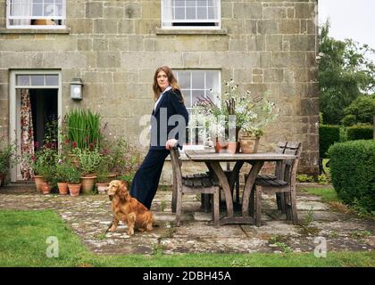 Interior designer Flora Soames and her dog Humbug, photographed at her Wiltshire home. Flora wears a tailormade corduroy suit from The Deck London. Stock Photo