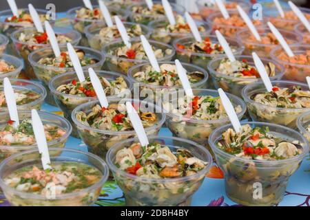 Display of different variety of ceviche in plastic glasses perfectly lined up with white spoons at Angelmo Bay market in Puerto Montt, Chile Stock Photo