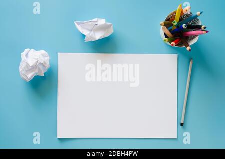 Blank notebook, set of colorful pencils and crumpled up papers on blue background. Paper background. Mock Up. View from above Stock Photo