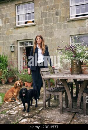 Interior designer Flora Soames and her dog Humbug, photographed at her Wiltshire home. Flora wears a tailormade corduroy suit from The Deck London. Stock Photo