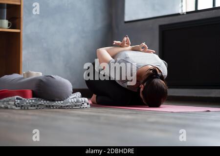 young woman sitting in child pose on a yoga mat Stock Photo