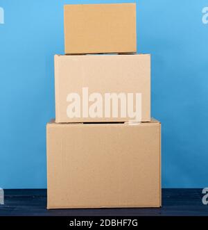 stack of cardboard boxes of brown kraft paper on a blue wooden table, moving concept Stock Photo