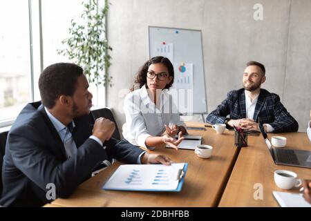 Coworkers At Corporate Meeting Discussing Work Sitting In Modern Office Stock Photo