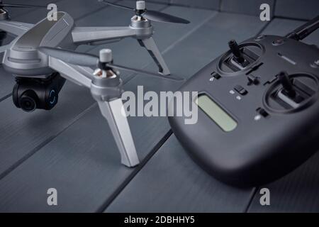 Close-up of quad-engine drone mounted camera and dual frequency radio control remote control in the background on gray wooden background Stock Photo