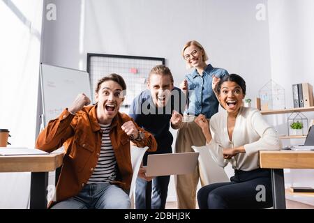 happy, young multiethnic businesspeople looking at camera and showing win gesture Stock Photo