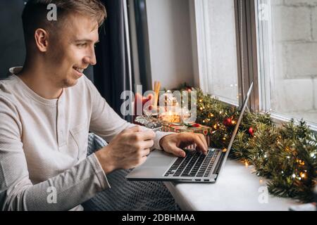 man customer wearing pajama shopping online using credit card making purchase in internet store at home office. Christmas gift box, New Year sale, xma Stock Photo