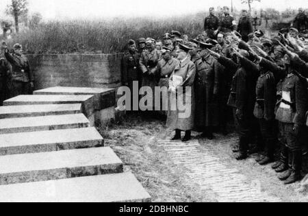 Adolf Hitler with his entourage at the military cemetery of Langemarck. Behind him is probably Werner von Brauchitsch in a leather coat. Hitler progandistically cultivated the myth of Langemarck with his visit. Stock Photo