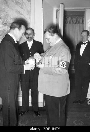 Paul Hartmann holds out the collection box of the WHW-Spende to Hermann Goering (right). The picture was taken at the festive performance for the 150th anniversary of the Staatliches Schauspielhaus. Stock Photo