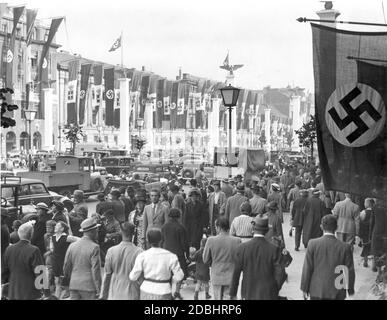 Benito Mussolini visited Germany from September 25 to 29, 1937. The picture shows people waiting in the morning in front of the Hotel Adlon in the street Unter den Linden in Berlin, for the Duce's later reception while traffic is still rolling on the street. The street has been decorated with numerous Nazi symbols and Italian flags. Stock Photo