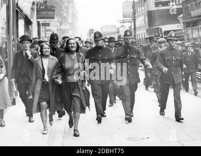 In the course of a clash with Communist demonstrators at an unemployment demonstration in London's Hyde Park, police escort two demonstrators down Oxford Street. Stock Photo