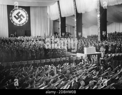 View of the opening event of the NSDAP party congress during the Horst-Wessel-Lied on the grandstand in the Luitpoldhalle on the Nazi party rally grounds in Nuremberg. In the 1st row, from right (left side): Julius Streicher, Adolf Hitler (behind him Wilhelm Brueckner), Rudolf Hess, Viktor Lutze, Heinrich Himmler, Franz Xaver Schwarz, Robert Ley, Joseph Goebbels. Right side: Hermann Goering. Stock Photo