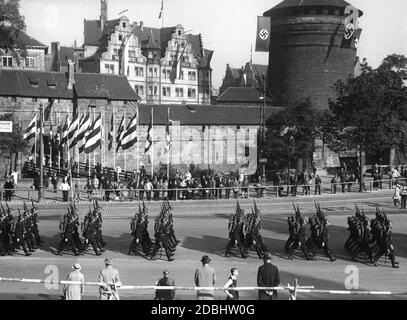 SS troops march in front of Nuremberg's Koenigstor on the Bahnhofsplatz during the Nazi Party Congress. In the background, the Hotel Victoria. Stock Photo